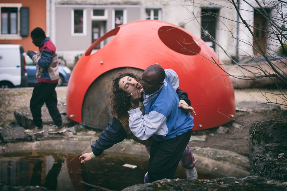 zwei junge Tänzer umarmen sich. Sie sind auf einem Spielplatz. Eine Mischung aus Spiel und Kampf.