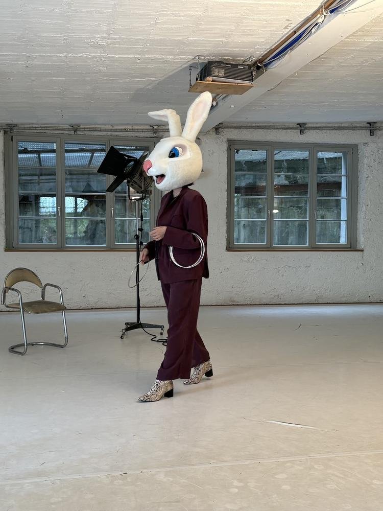 eine Person mit flauschiger "weisses Kaninchen" Maske steht auf der Studiobühne mit Jonglagereifen.